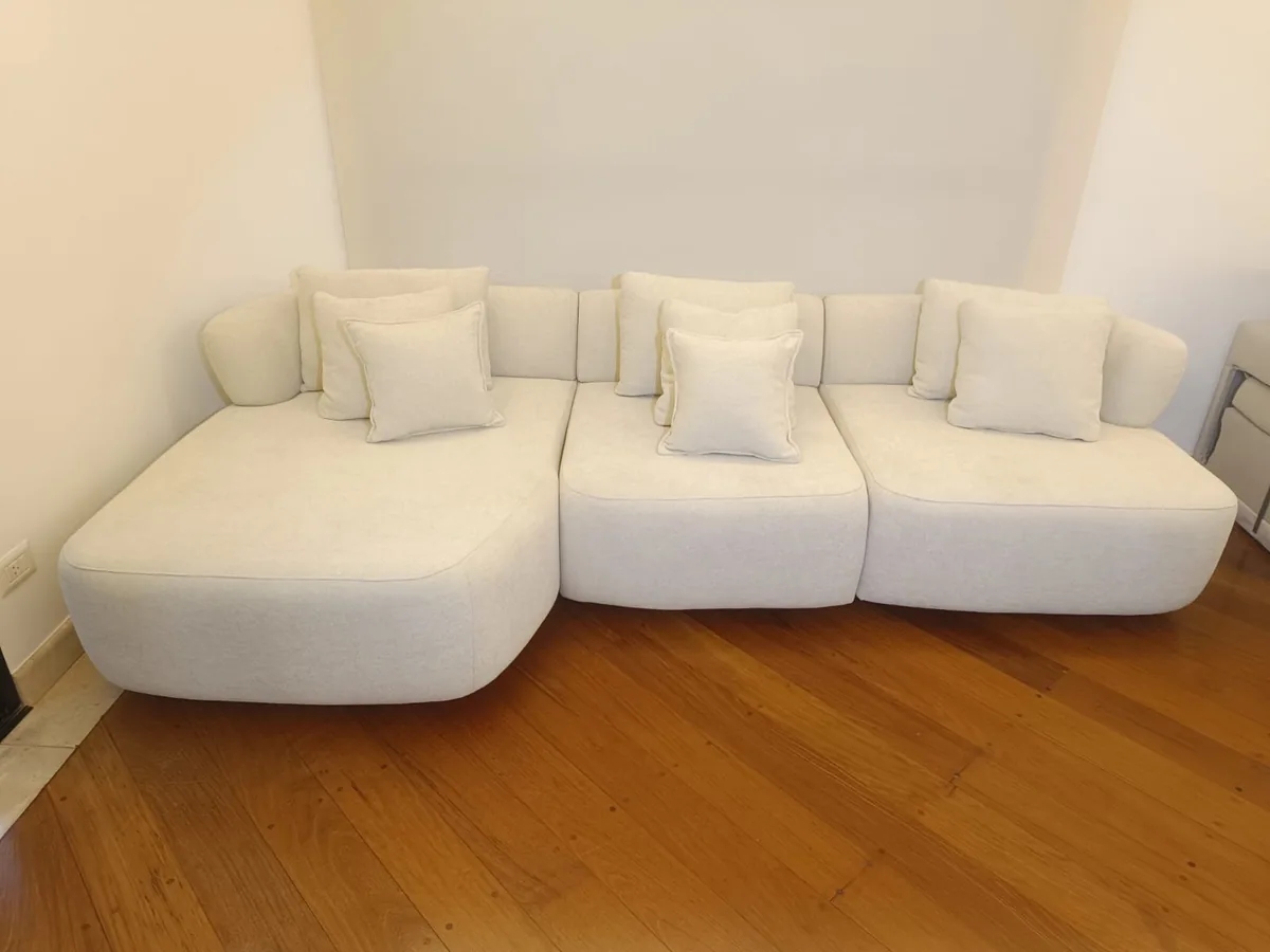 Sofá curvo de bouclé branco sobre piso de madeira